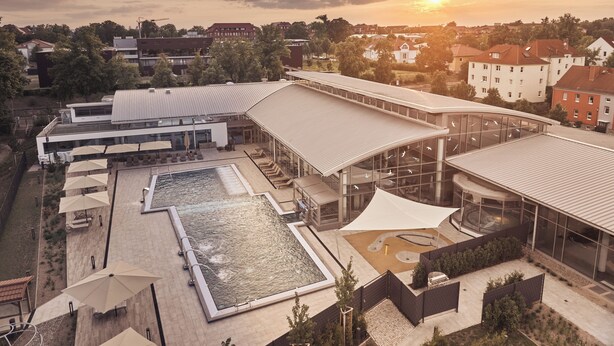 Ein modernes Hotel mit Schwimmbad, Sitzgelegenheiten im Freien und einer großen Glasfassade.