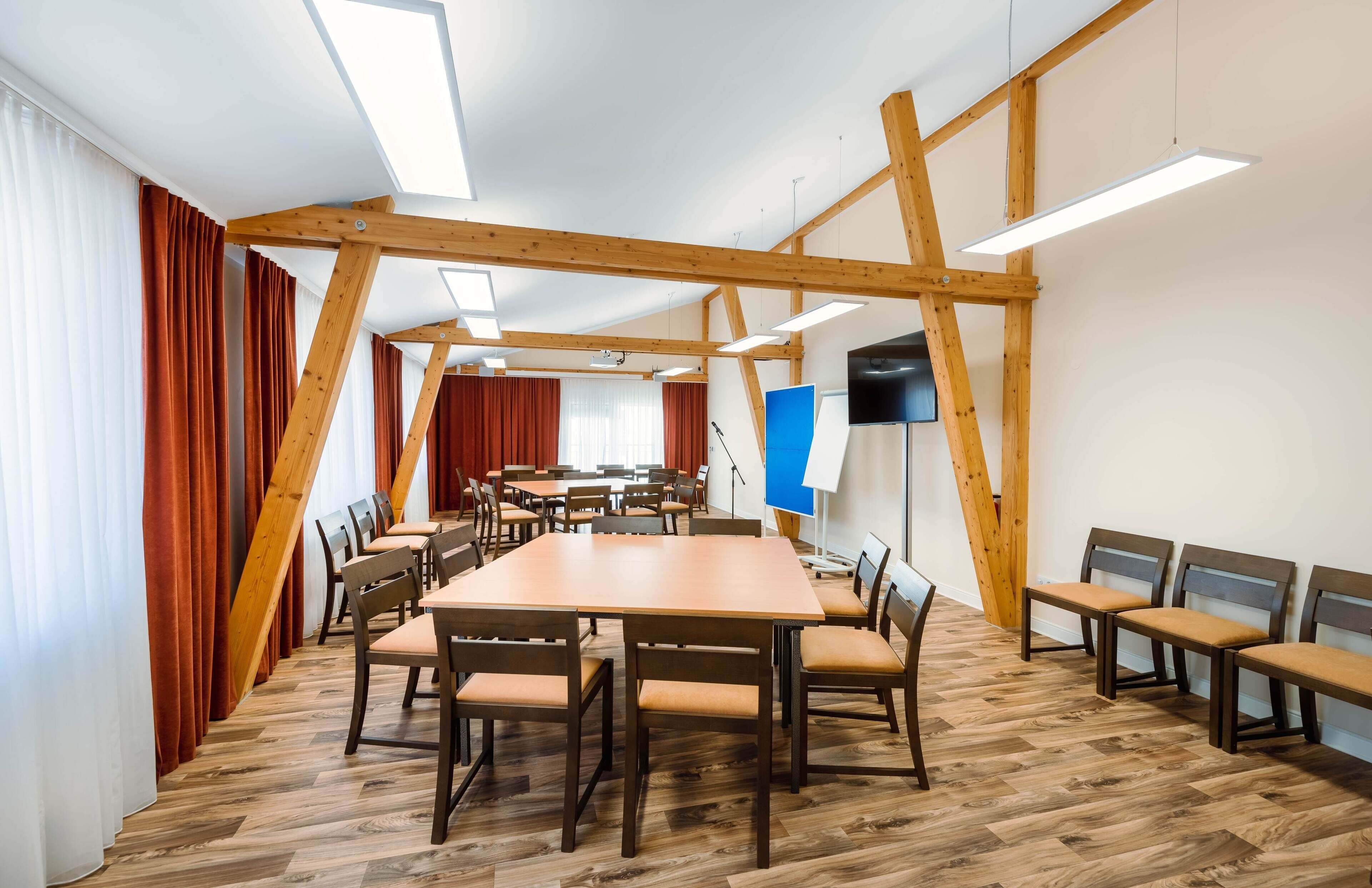 A conference room with a wooden ceiling, large tables, and chairs.