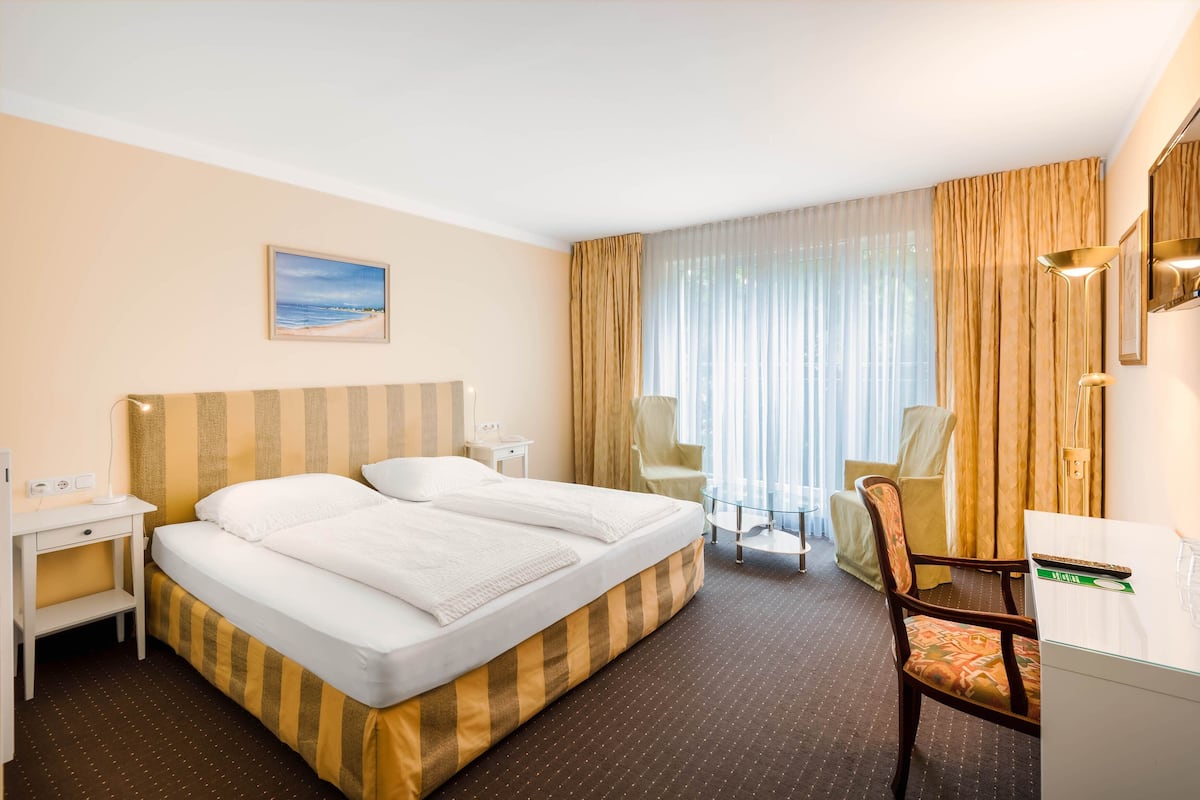 Una habitación de hotel con una cama grande, un escritorio, una silla y un televisor.