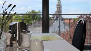 Ein Balkon mit Esstisch, Blick auf einen Turm und ein Stuhl.
