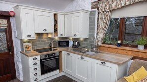 A compact kitchen with white cabinets, a built-in oven, a microwave, and a sink.