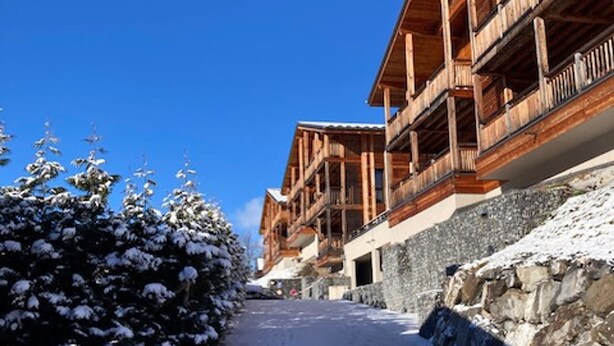 Un sendero cubierto de nieve que conduce a un edificio de madera con balcones.