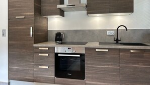 Cocina moderna con alacenas de madera oscura, horno Bosch, cafetera y campana extractora de acero inoxidable.