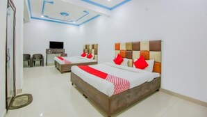 Una habitación de hotel con dos camas, televisión, escritorio y una silla.