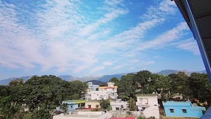 Zona residencial con casas y montañas al fondo bajo un cielo parcialmente nublado.