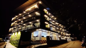Un hotel de varios pisos con un atrio central, zona de estar al aire libre y aparcamiento.