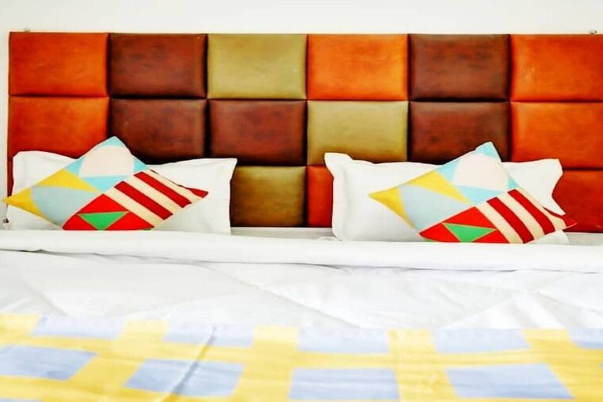Una cama con un colchón blanco y una colcha de cuadros coloridos.