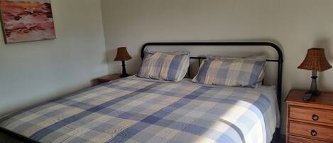 A bedroom with a bed, two nightstands, a lamp on each nightstand, and a painting on the wall.
