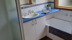 A bathroom with a white sink, blue countertop, and a wooden floor. - By the Beach (Apollo Bay)