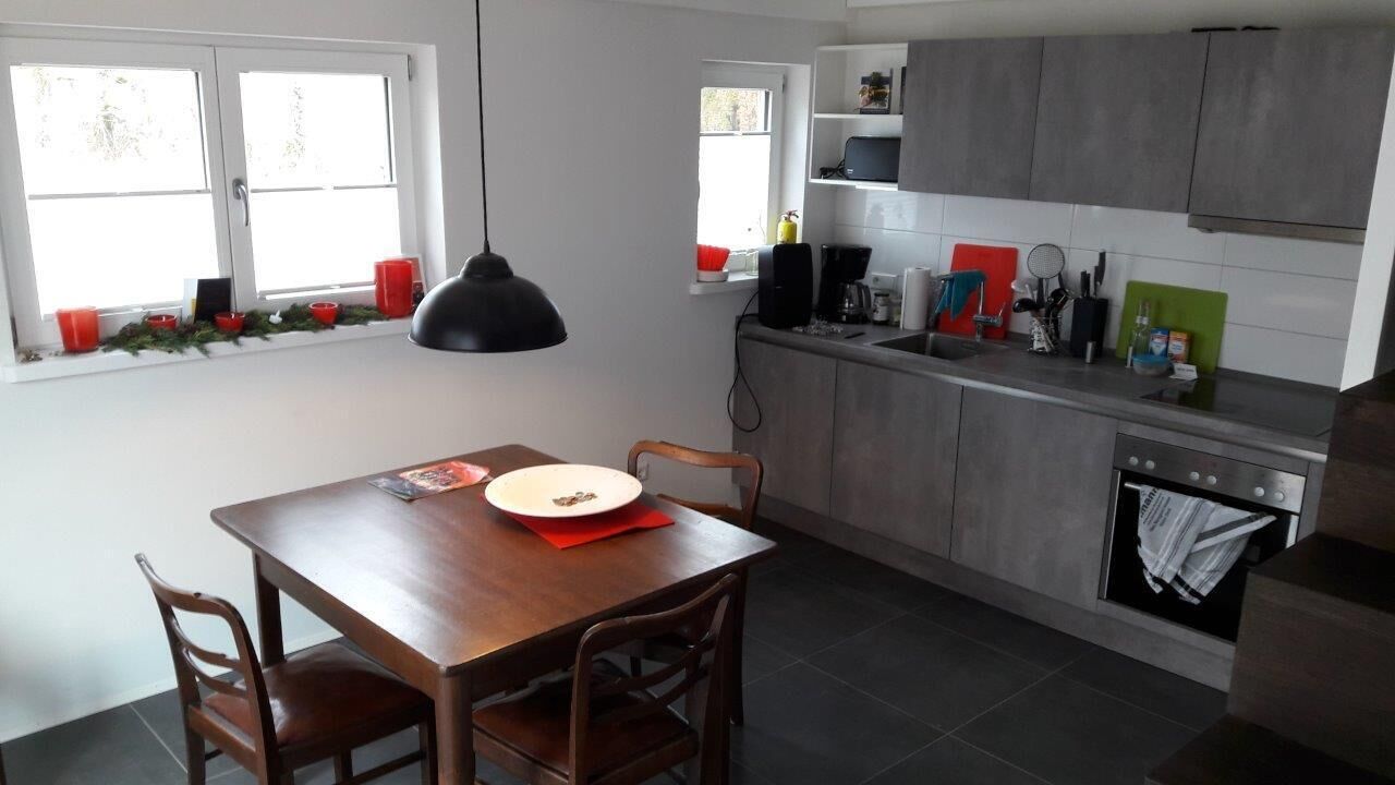 A compact kitchen with a dining table, chairs, a pendant light, and a built-in oven.
