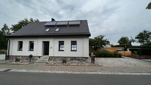 Et etplanshus med mørkt tag, solpaneler og en stensokkel.