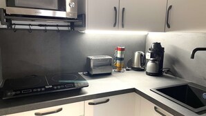 Una cocina equipada con microondas, tostadora, hervidor y cocina de inducción.