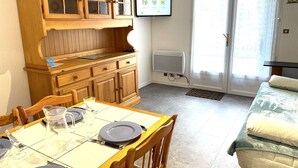 Un comedor con un aparador de madera, un televisor montado en la pared y un ventanal corredero que da a un espacio exterior.