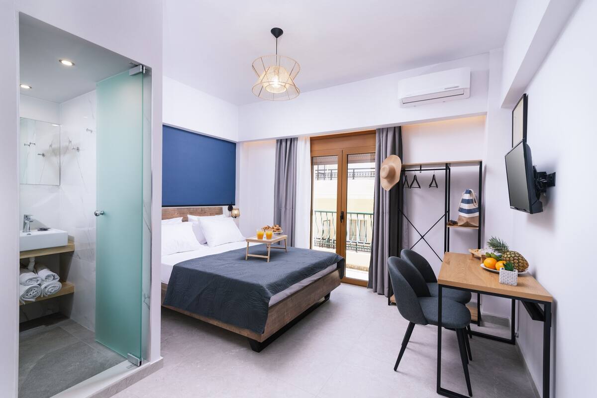 Een moderne hotelkamer met een bed, een bureau, een stoel, een balkon en een badkamer.