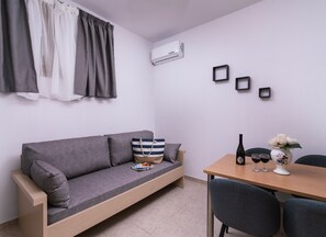 Un espace de vie compact comprenant un canapé, une table à manger et un petit coin cuisine.