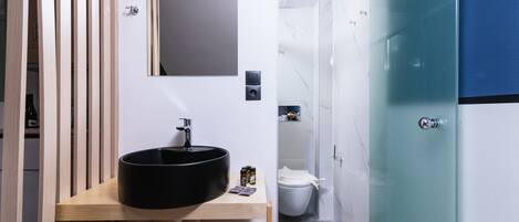 A modern bathroom with a wooden vanity, black sink, and white towels.