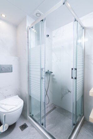 Une salle de bain moderne dotée d’une douche à parois de verre, de toilettes et d’un sol en marbre.