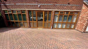 A brick building with large glass doors and windows, a paved driveway, and a parked car visible through the glass. - Cosy Homely Apartment Close to Lincoln City Centre (Lincoln)