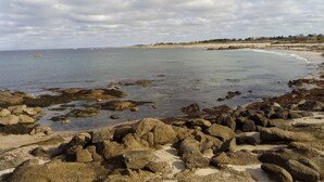 A rocky beach with calm water, distant shoreline, and overcast sky. - Cozy Seaside Cottage with Terrace, Private Garden & Electric Car Charging (Vicq-sur-Mer)