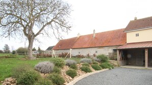 A rural property with a gravel driveway, stone walls, and a large tree. - Charming house with enclosed garden in Cotentin Marshes (Liesville-sur-Douve)