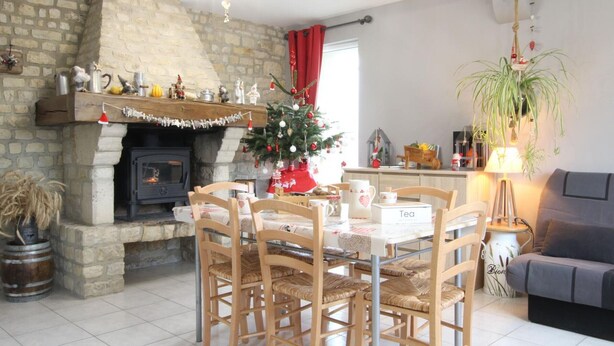 A cozy living room with a fireplace, a dining table with chairs, a Christmas tree, and a sofa. - Charming house with enclosed garden in Cotentin Marshes (Liesville-sur-Douve)