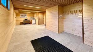Un interior de madera con techo inclinado, un felpudo negro en la entrada y una pequeña zona de kitchenette.