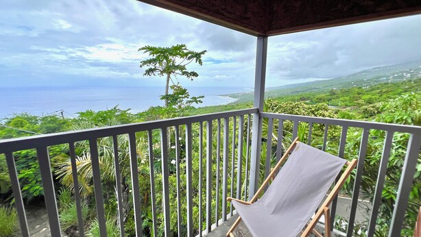 A wooden deck with two foldable chairs and a view of the ocean and greenery. - L'ECRIN DUBUISSON Spacious villa in lush garden with whirlpool bath (Saint-Leu)