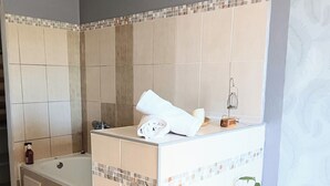 A bathroom with a bathtub, a shower area, a sink, and a potted plant. - L'ECRIN DUBUISSON Spacious villa in lush garden with whirlpool bath (Saint-Leu)