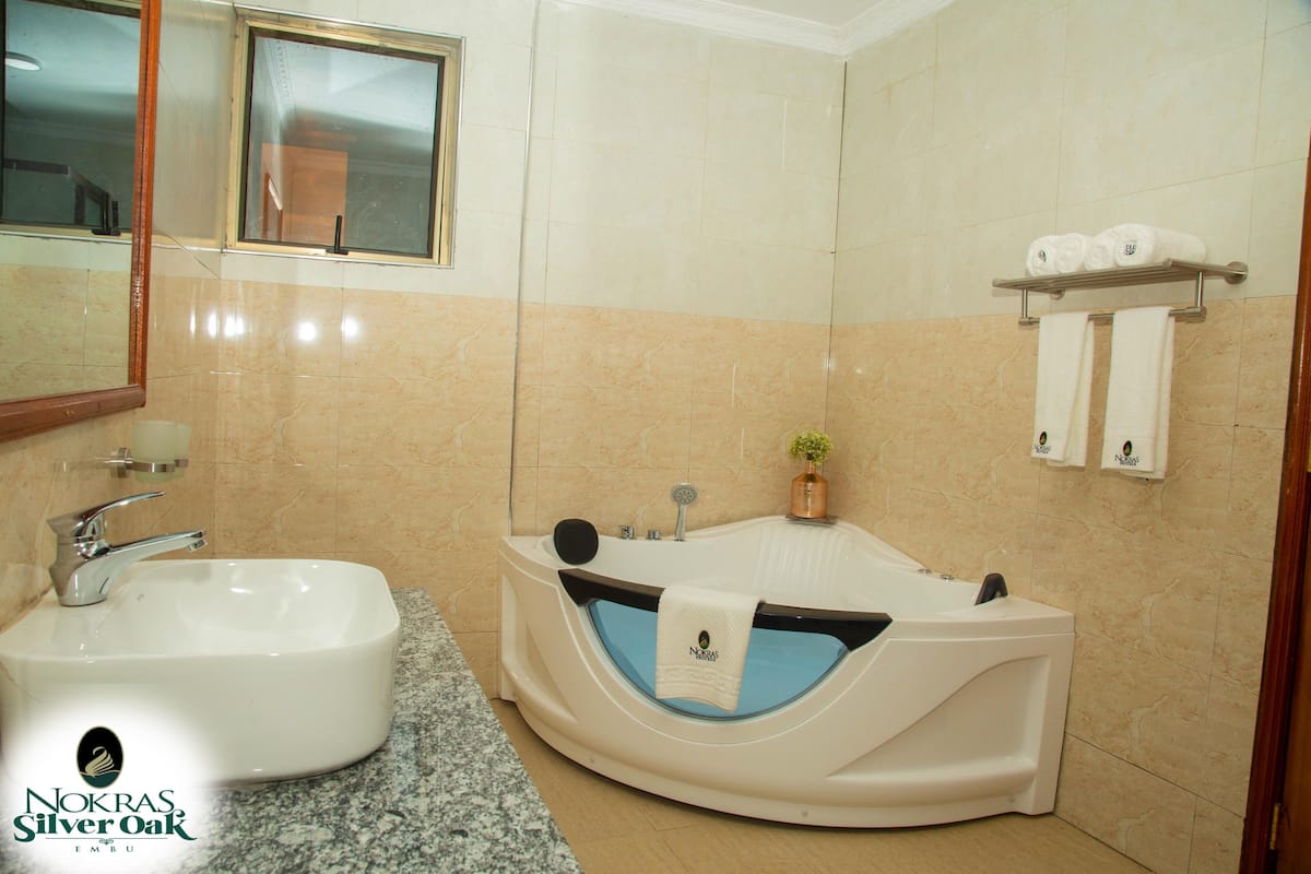Casa de banho com lavatório, banheira e toalhas numa prateleira.