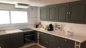 A kitchen with dark green cabinets, a white countertop, and a tiled floor. - THE SIGNORET HOUSE IN THE COUNTRYSIDE NEAR BORDEAUX (Baron)