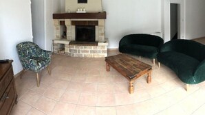 A living room with a stone fireplace, two dark green sofas, a patterned armchair, and a wooden coffee table. - THE SIGNORET HOUSE IN THE COUNTRYSIDE NEAR BORDEAUX (Baron)
