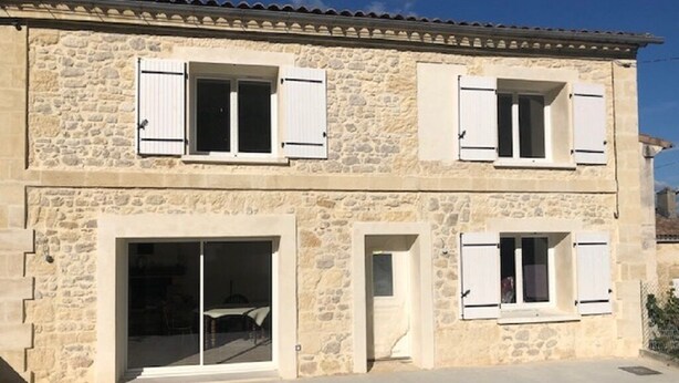 A two-story stone building with white shutters, a large sliding glass door, and a small door. - THE SIGNORET HOUSE IN THE COUNTRYSIDE NEAR BORDEAUX (Baron)