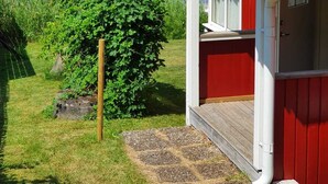 Una casa con techo rojo y paredes blancas, un muelle de madera y vistas a un lago.