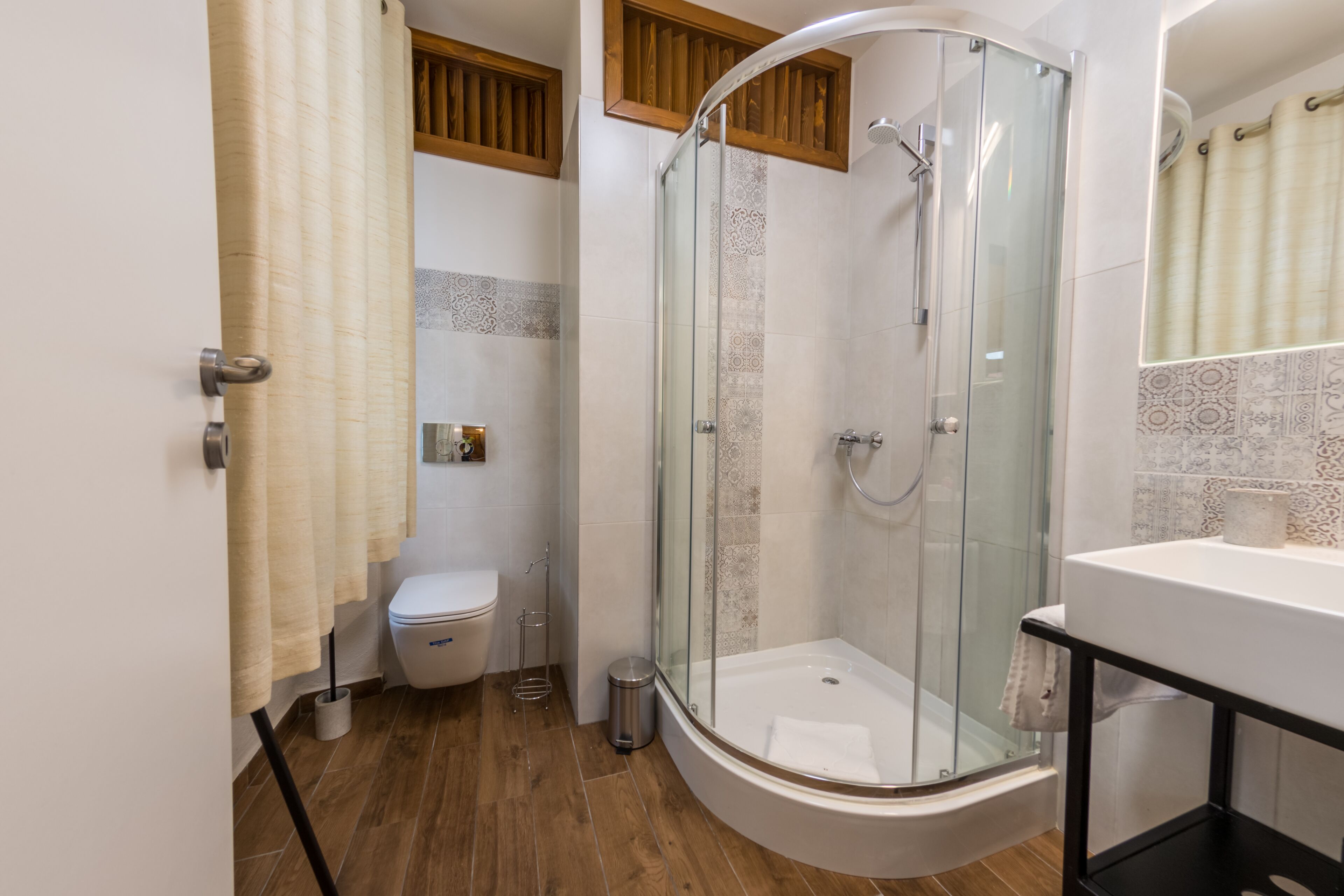 A modern bathroom with a glass-enclosed shower, a toilet, and a sink.