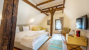 Ein Schlafzimmer mit Holzboden, einem Bett, einem Schreibtisch und einem Fernseher.