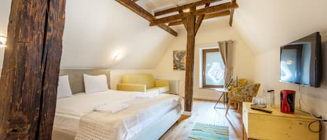 Un dormitorio con techo de madera, una cama, un escritorio y un televisor.