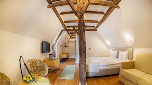 A cozy attic bedroom with a wooden ceiling, a bed, a sofa, a TV, and a small table with fruit. -  Rossmarkt Haus (Brasov)