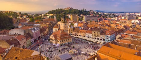 A historic square with a central fountain, surrounded by traditional buildings with red-tiled roofs.