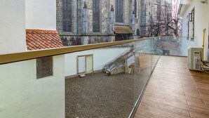 A modern interior with a glass balcony overlooking a historic building with a church steeple. -  Rossmarkt Haus (Brasov)