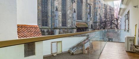 A modern interior with a glass balcony overlooking a historic building with a church steeple.