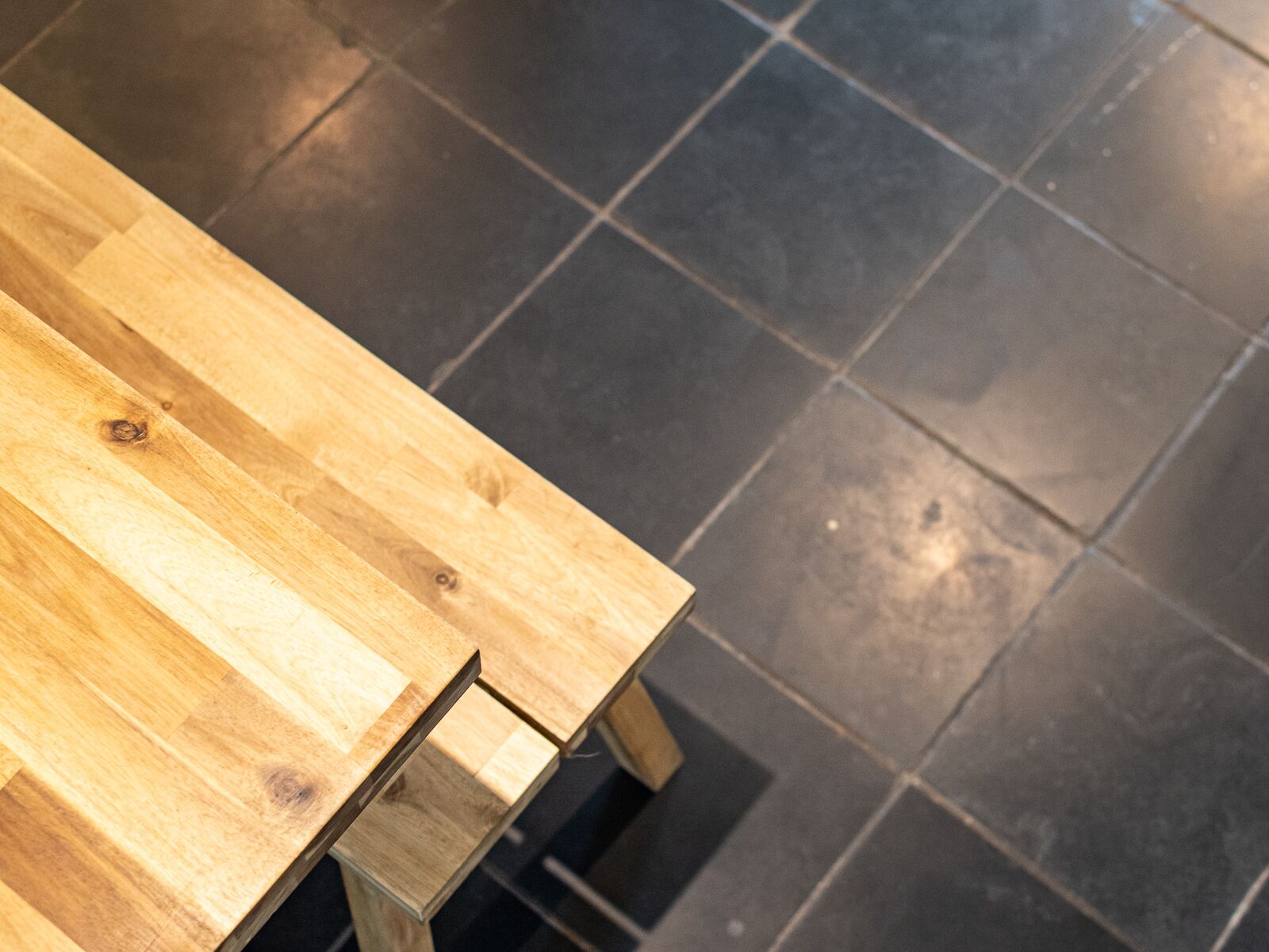 Une table en bois posée sur un sol carrelé foncé.