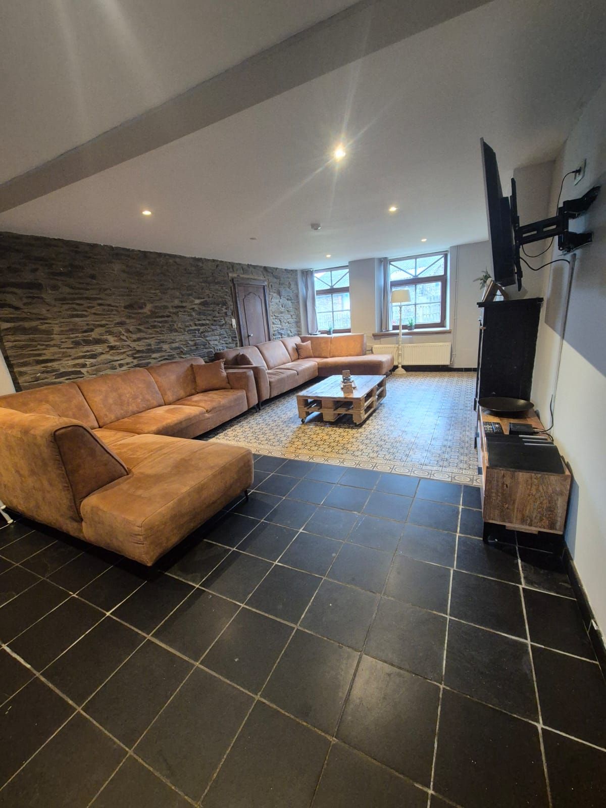 A modern living room with a sectional sofa, a coffee table, and a fireplace.