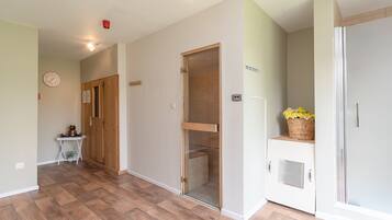 A hallway with wooden flooring, a clock, a wooden door, a glass door, and a refrigerator with flowers.