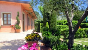 A well-maintained garden with various flower beds and neatly trimmed hedges in front of a building with a pink facade.