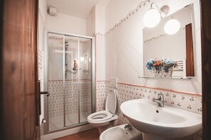 A bathroom with a glass-enclosed shower, a toilet, and a sink with a mirror above. - Apartment with a pool in the Tour des Palmiers with ocean views—5 minutes from the beach (Marche)