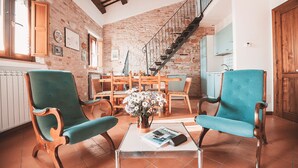 Amplia sala de estar con dos sillones azul verdoso, una mesa de centro de madera y una escalera que conduce a un nivel superior.