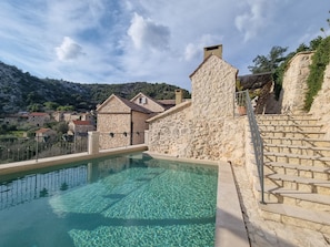 A stone pool with clear water, surrounded by stone walls and a staircase leading up. - Rustic luxury villa Fulmin (Hvar)