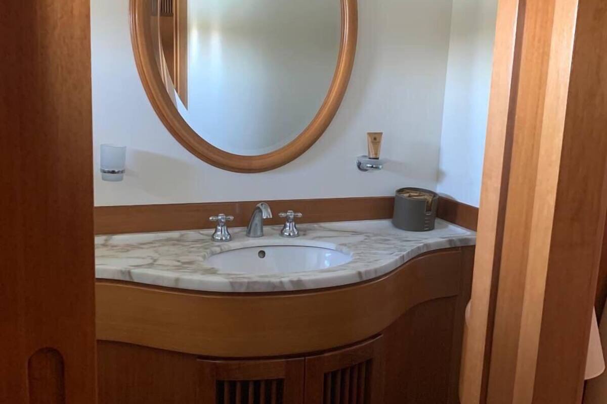 Une salle de bain avec un meuble-lavabo en bois, un lavabo en marbre et un grand miroir.