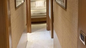 Un pasillo estrecho con una cama al final, enmarcado por paneles de madera y una alfombra blanca.