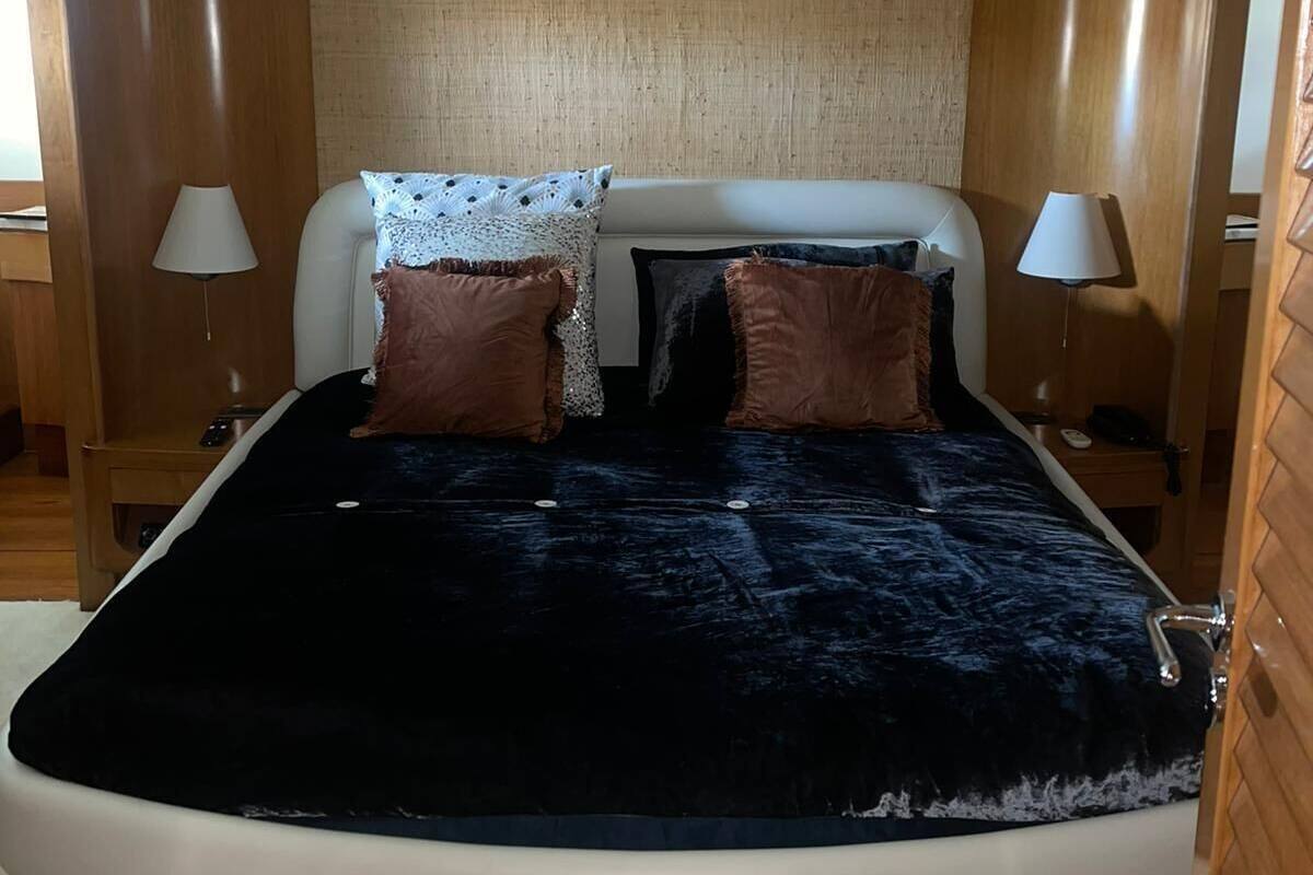 Une chambre à coucher moderne avec un lit aux lignes courbes, deux lampes de chevet et une tête de lit texturée.